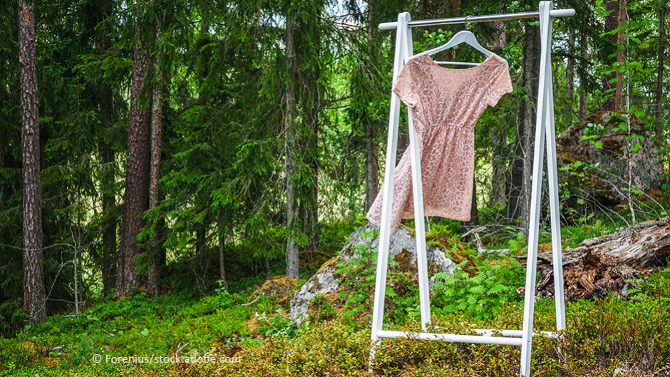 Kleid hängt im Wind wehend auf einem Kleiderbügel an einem Kleiderständer im Wald